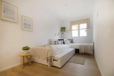a white bedroom with two beds and a window at Vivalidays Apartour - Calella in Calella
