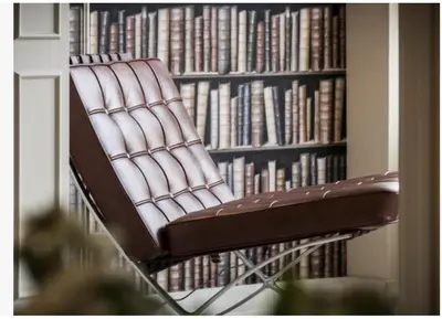 a brown leather chair in front of a book shelf at Glocal Apartments Barcelona in Barcelona