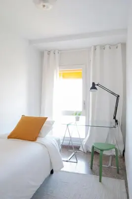 a white bedroom with a bed and a green stool at Apartment near the beach and Port Marina of Premia in Premiá de Mar