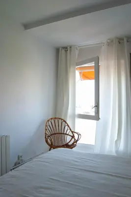 a bedroom with a bed and a chair in front of a window at Apartment near the beach and Port Marina of Premia in Premiá de Mar