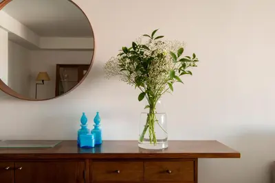 a vase of flowers on a dresser with a mirror at Apartment near the beach and Port Marina of Premia in Premiá de Mar