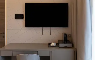 a tv hanging on a wall with a table and a chair at AB BOUTIQUE HOTEL - Adults only in Sant Vicenç de Montalt