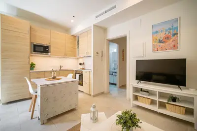 a living room with a large television and a kitchen at NICE CENTRIC APARTMENT in Vilanova i la Geltrú