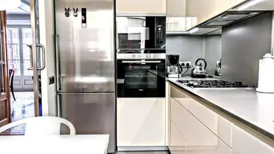 a stainless steel refrigerator in a kitchen with white cabinets at BizFlats Eixample Apartments in Barcelona