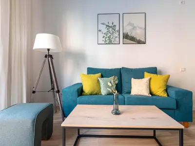 a living room with a blue couch with yellow pillows at Limehome Barcelona Carrer de Besalú 90 - estancia temporal in Barcelona