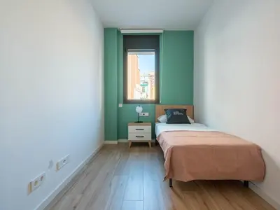 a bedroom with green walls and a bed with a window at Limehome Barcelona Carrer de Besalú 90 - estancia temporal in Barcelona