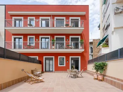 a red building with a patio in front of it at Limehome Barcelona Carrer de Besalú 90 - estancia temporal in Barcelona