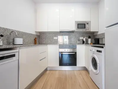 a white kitchen with white cabinets and a washer and dryer at Limehome Barcelona Carrer de Besalú 90 - estancia temporal in Barcelona