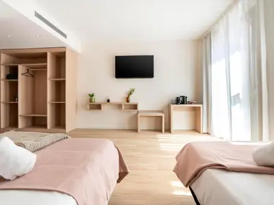 a bedroom with two beds and a tv on the wall at Limehome Barcelona Carrer de Besalú 82 in Barcelona