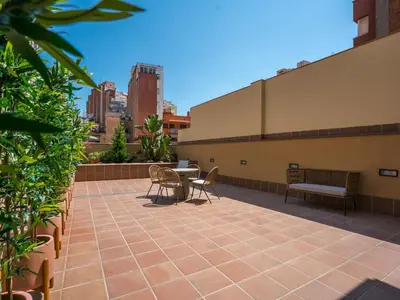 a patio on the roof of a building with tables and chairs at Limehome Barcelona Carrer de Besalú 82 in Barcelona