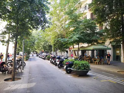 a row of motorcycles parked on a street with tables and chairs at ApartEasy - Eixample Center in Barcelona