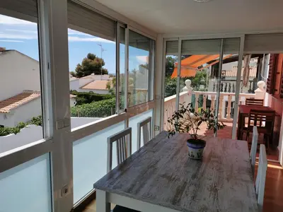 a wooden table on a balcony with windows at Villa Playa y Montaña in Cunit