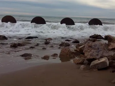 a beach with rocks and the ocean with waves at Villa Playa y Montaña in Cunit