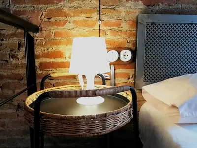 a lamp on a table next to a bed at Mazi Apartments Penthouse in Badalona