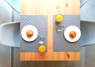 a table with two plates of food and two glasses of orange juice at Mazi Apartments Chic in Badalona