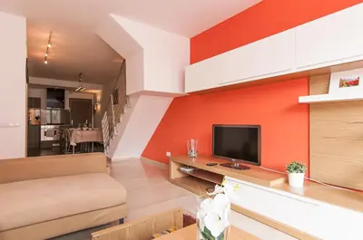 a living room with an orange accent wall at Private terrace at Sagrada Familia in Barcelona
