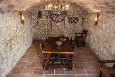 a dining room with a table and a chandelier at Masia St Salvador 1582 in Cubelles