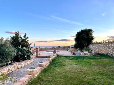 a garden with a stone wall and a pond at Masia St Salvador 1582 in Cubelles