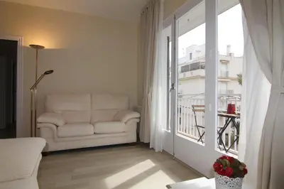 a living room with a couch and a large window at Rubí: Luminoso apartamento a 1 minuto de la playa in Sitges