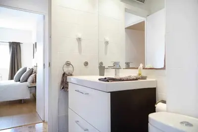a white bathroom with a sink and a mirror at SAGRADA FAMILIA VIEWS Nos preocupa su seguridad. in Barcelona