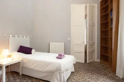 a bedroom with a white bed and a table and shelves at Modernist Apartment Barcelona in Barcelona