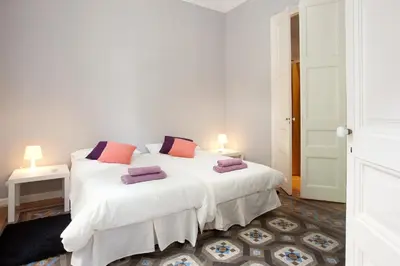 a bedroom with a bed with white sheets and purple pillows at Modernist Apartment Barcelona in Barcelona