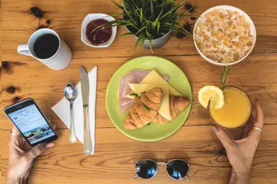 a table with a plate of food and a person holding a cell phone at Sant Jordi Hostels Rock Palace in Barcelona