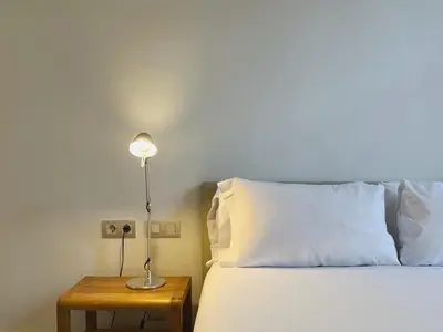 a bed with a white pillow and a lamp on a table at Stay Unique Apartments Bruc in Barcelona