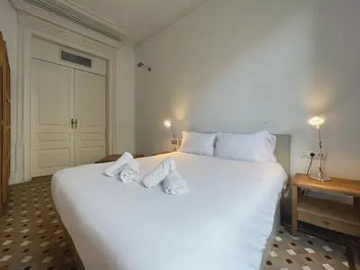 a bedroom with a large white bed with two pairs of shoes on it at Stay Unique Apartments Bruc in Barcelona