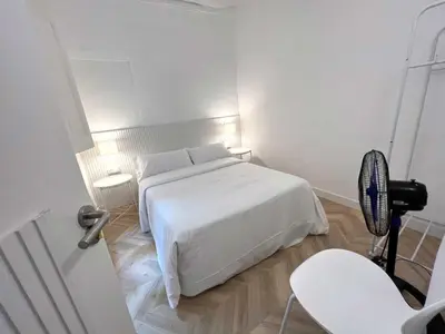 a white bedroom with a white bed and a chair at The MO GOTIC in Barcelona