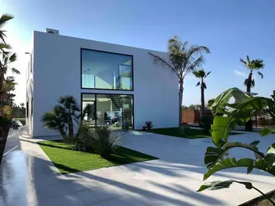 a large white house with palm trees in front of it at Contemporary villa near Sitges Hills in Avinyonet