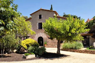 an old stone house with a tree in a yard at La Mer Hotel in Cabrera de Mar