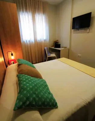 a hotel room with a bed with two green pillows at Can Mir Badalona in Badalona