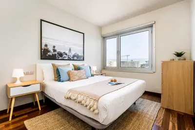 a bedroom with a large bed and two windows at Lodging Apartments Forum Llull in Sant Adria de Besos