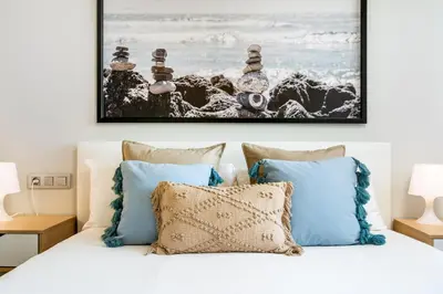 a bedroom with a white bed with blue pillows at Lodging Apartments Forum Llull in Sant Adria de Besos