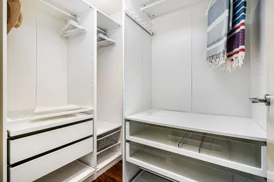 a walk in closet with white cabinets and glass shelves at Lodging Apartments Forum Llull in Sant Adria de Besos