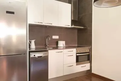 a kitchen with white cabinets and a stainless steel refrigerator at Apart céntrico con terraza en Gracia in Barcelona