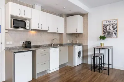 a kitchen with white cabinets and a washer and dryer at Lodging Apartments Liceu G1 in Barcelona