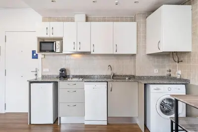 a kitchen with white cabinets and a washer and dryer at Lodging Apartments Liceu G1 in Barcelona