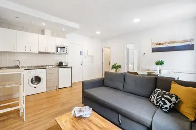 a living room with a couch and a kitchen at Lodging Apartments Liceu G2 in Barcelona