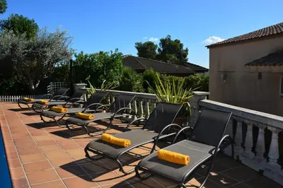 a row of chairs sitting on a patio at Villa Sitges Ilusión 15 minutes by car from Sitges Sleeps 16 people XXL swimming pool in Olivella