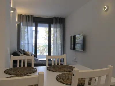 a living room with a table and chairs and a window at Family Apartment in Vilanova i la Geltrú