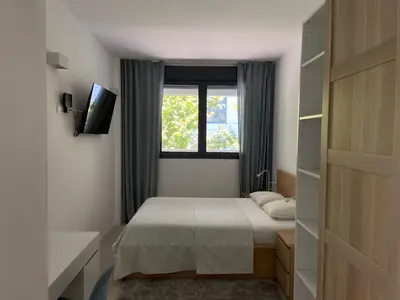 a small bedroom with a bed and a window at Family Apartment in Vilanova i la Geltrú