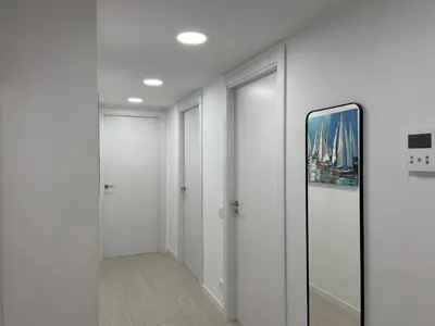 a hallway with white walls and a framed picture on the wall at Family Apartment in Vilanova i la Geltrú