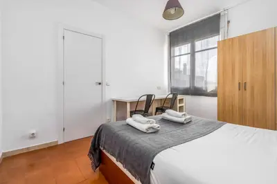 a bedroom with a bed with two chairs and a window at Arc de Triomf Base 4BR for 5 Lift in Barcelona
