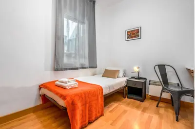 a small bedroom with a bed and a chair at Arc de Triomf Base 4BR for 5 Lift in Barcelona