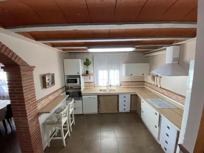 a kitchen with white cabinets and a brick wall at Molí den burch in Santa Eulalia de Ronsaná