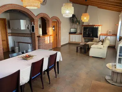 a kitchen and living room with a table and chairs at Molí den burch in Santa Eulalia de Ronsaná