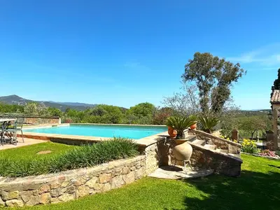 a swimming pool in a yard with a stone wall at Masia Can Viver - Olive oil tourism B&B in Bigues i Riells