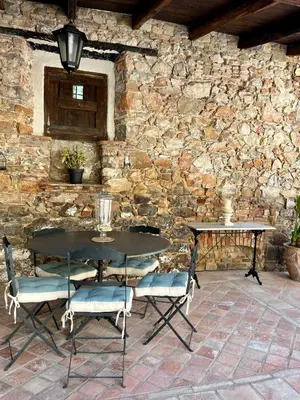a table and chairs in front of a stone wall at Masia Can Viver - Olive oil tourism B&B in Bigues i Riells